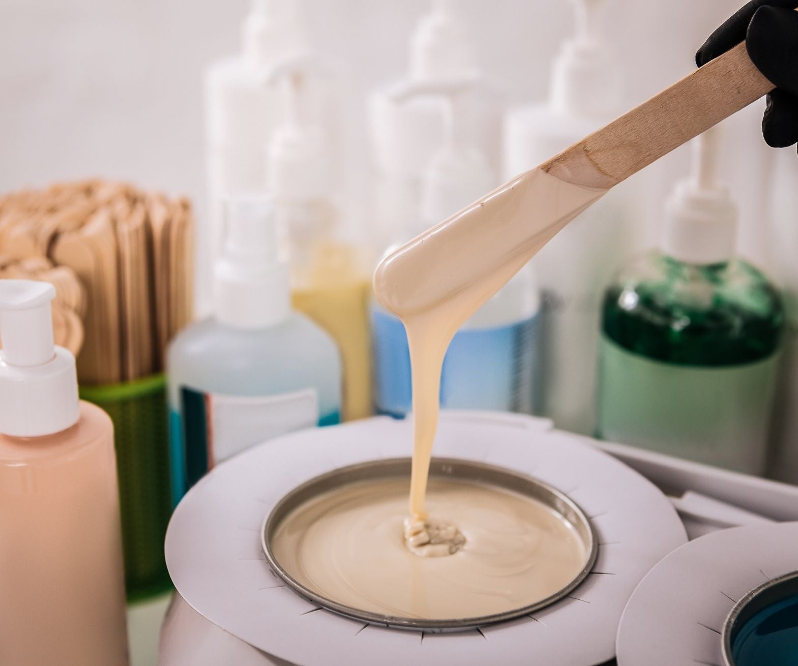 Warm wax being lifted on a spatula in a waxing salon